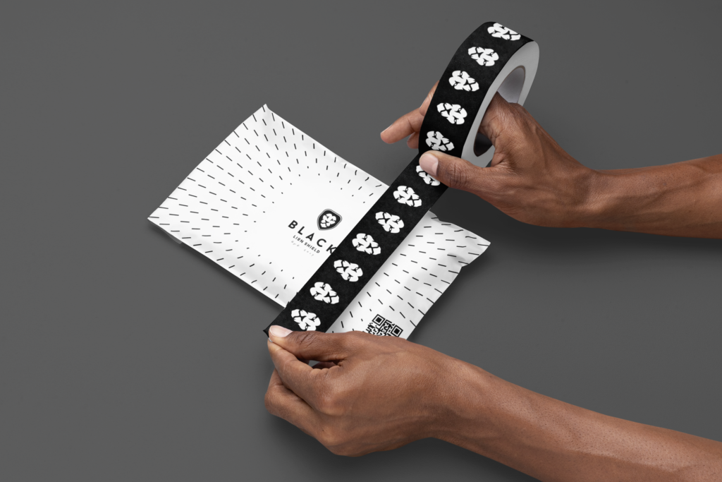 A man applying branded "BLACK" tape to a poly mailer, highlighting the attention to detail and professional packaging process.